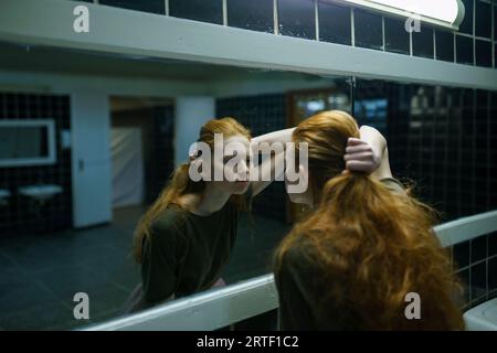 Eine junge Frau, die im Spiegel im öffentlichen Badezimmer schaut Stockfoto