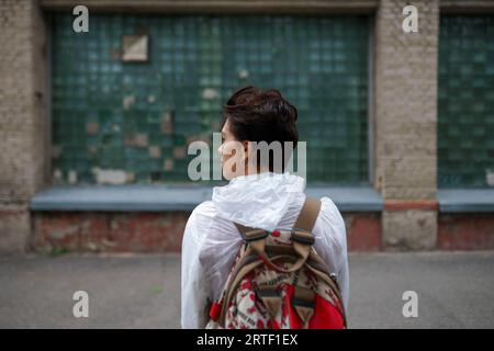 Rückansicht einer jungen Frau, die wegschaut, während sie mit Rucksack in der Stadt steht Stockfoto