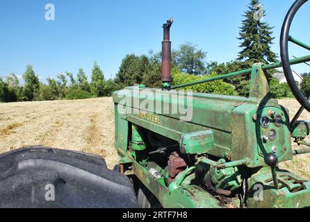 Blick vom Fahrersitz eines alten John Deere-Traktors auf das Heufeld vor uns an einem sonnigen Tag mit klarem blauen Himmel im ländlichen pazifischen Nordwesten Stockfoto