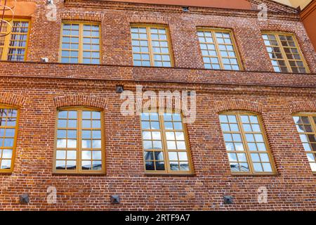 Klassische Fassade aus rotem Ziegelstein mit mehreren Fenstern. Stockfoto