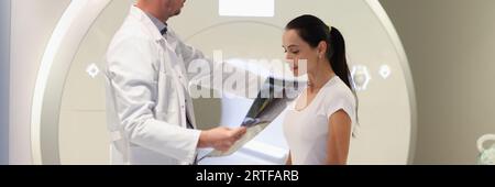 Der Radiologe betrachtet die MRT-Ergebnisse und legt seine Hand auf die Schulter eines traurigen Patienten. Stockfoto