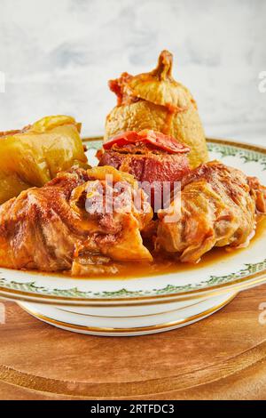 Gefüllte Zucchini, Paprika und Kohlrollen auf Teller mit einem Ornament auf Holzständer Stockfoto