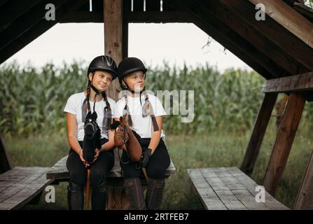 Porträt von Mädchen Jockeys, die auf einem Holztisch unter einem Baldachin sitzen. Stockfoto