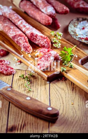 Traditionelles spanisches Fuet auf hölzernem Hintergrund. Trocken gereifte Schweinswürste mit delikaten Geschmack. Stockfoto
