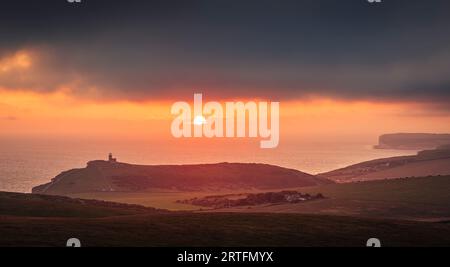 Dramatischer Himmel und Sonnenuntergang hinter dem Leuchtturm Belle Tout vom Klippenrand des Beachy Head an der Südküste von Sussex im Südosten Englands Stockfoto