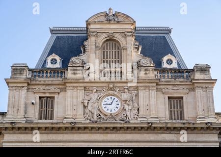 Detailansicht der antiken Fassade mit Uhr und Steinschnitzerei der Präfektur Herault, Montpellier, Frankreich Stockfoto