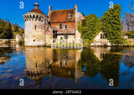 Reflexionen im Graben an einem sonnigen Frühlingstag in Scotney Castle, Kent, Großbritannien Stockfoto