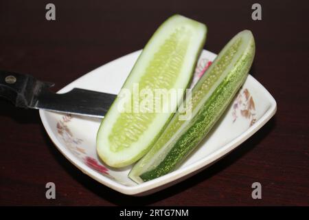 Eine Gurke und ein Messer auf einem Teller. Stockfoto