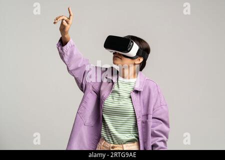 Mädchen in der Virtual-Reality-Brille drückt auf den virtuellen Knopf. Moderne Technologien für Studium und Kommunikation. Stockfoto