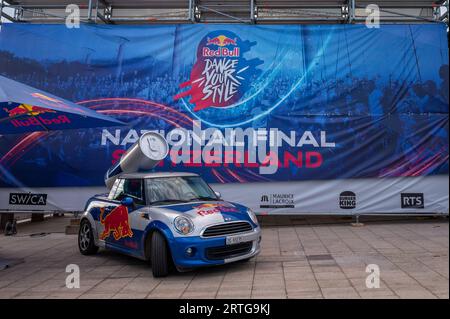 Lausanne, Waadtländer Kanton, Schweiz - 20. August 2023: Red Bull Werbung Mini Cooper Auto mit Logo. Riese Red Bull Energy Drink Dose auf dem Wagen Stockfoto