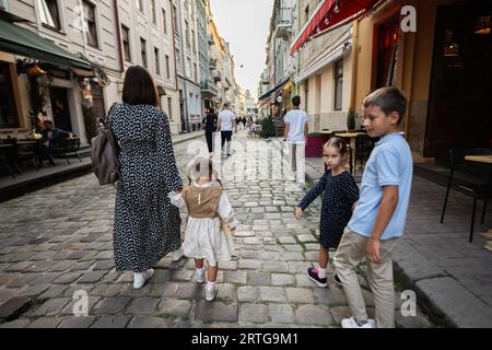Rückansicht der Familie mit vier Kindern, die in der Stadt Lemberg, Ukraine, spazieren gehen. Stockfoto