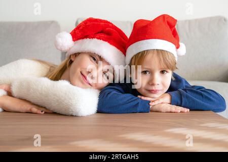 Nahaufnahme eines Porträts von niedlichen Kindern in Weihnachtsmannhüten zu Hause Stockfoto