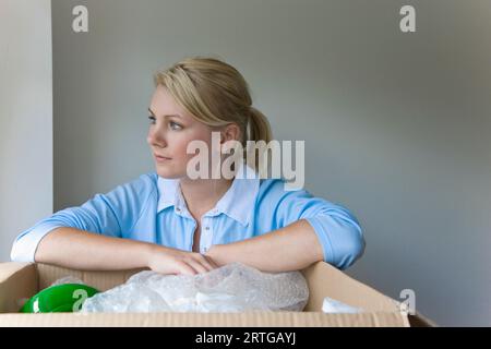 Nahaufnahme einer jungen Frau mit Armen ruht auf einem Karton mit Blick Stockfoto