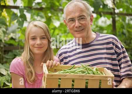 Junge Mädchen und Reife Mann hält eine Kiste mit Bohnen Stockfoto