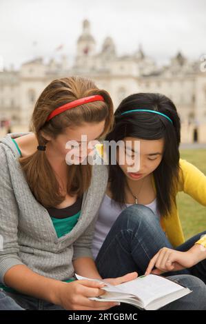 Zwei Teenager Mädchen vor Horse Guards Parade in London ein Buch lesen Stockfoto