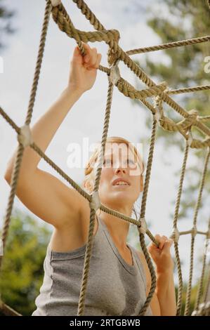 Junge Frau am Hindernis-Parcours klettern ein Gepäcknetz Stockfoto