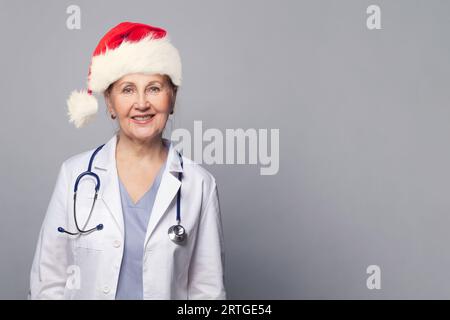 Weihnachtsporträt eines Weihnachtsarztes in professioneller medizinischer Uniform und rotem Weihnachtsmannhut Stockfoto