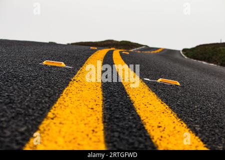 Die beiden gelben Linien erstrecken sich entlang einer Straße von einem Punkt zum anderen Stockfoto