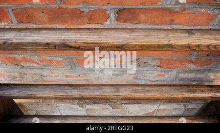 Abstrakter rauer dunkler Hintergrund aus gemischten Materialien, Kombination aus Holz, Ziegel und Stein in der Textur eines Fassadenfragments, Außendetails Stockfoto