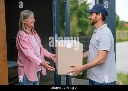 Die Frau nimmt die Lieferung von Kisten vom Lieferer an. Stockfoto
