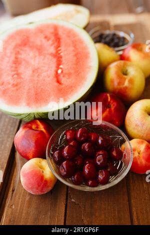 Von oben appetitliche Schwarzkirschen, Melone, Äpfel und Pfirsiche auf Holztisch angeordnet Stockfoto