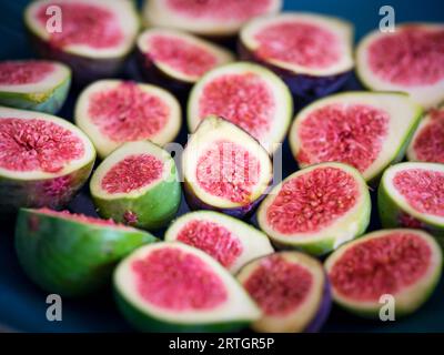 Nahaufnahme von halbierten Reifen, ungeschälten tropischen Feigenfrüchten auf blau glasierter Keramikplatte Stockfoto