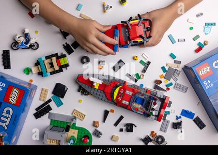 Riga, Lettland - 12. September 2023: Kind spielt mit Lego-Konstrukteur auf dem Tisch. Bau eines Feuerwehrwagens Stockfoto