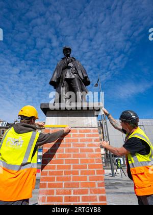 Edinburgh, Schottland, Großbritannien. September 2023. Die neu renovierte Statue von Sherlock Holmes wurde heute von Sir Arthur Conan Doyles Verwandter Tania Henzell und dem Verkehrskonventor Scott Arthur an einem neuen Ort am Picardy Place enthüllt. Die lebensgroße Bronzeskulptur, die den Geburtsort des Schöpfers des Supersleuth, Sir Arthur Conan Doyle, markiert, wurde 2018 entfernt, während Straßenbahnen zu Newhaven-Werken durchgeführt wurden. Es wurde von Black Isle Bronze in Nairn renoviert. Bild: Die Arbeiter machen den Sockel mit der Statue zum letzten Schliff. Iain Masterton/Alamy Live News Stockfoto