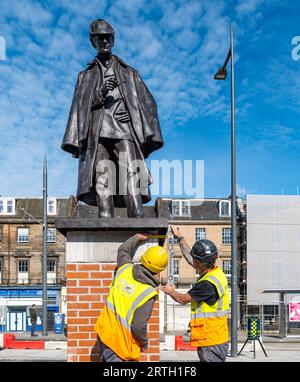 Picardy Place, Edinburgh, Schottland, Vereinigtes Königreich, 13. September 2023, Sherlock Holmes kehrt zurück: die neu renovierte lebensgroße Bronzestatue erinnert an den Geburtsort seines Schöpfers, Sir Arthur Conan Doyle. Es wurde von Black Isle Bronze renoviert. Auf dem Bild: Arbeiter haben der Statue den letzten Schliff gegeben. Sally Anderson/Alamy Live News Stockfoto