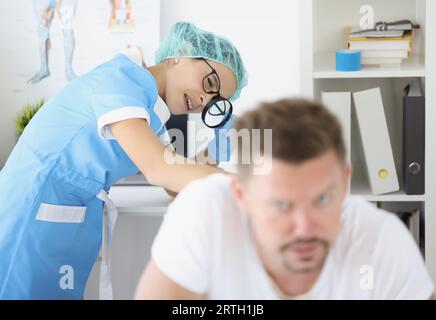 Frau Dermatologe untersuchen männlichen Patienten Körper, überprüfen Sie die Haut auf dem Rücken mit Lupe Stockfoto