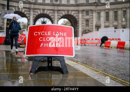 LONDON – 24. April 2023: Ein rotes Schild mit geschlossener Radspur warnt vor Straßenarbeiten am Admiralty Arch an einem regnerischen Tag. Stockfoto