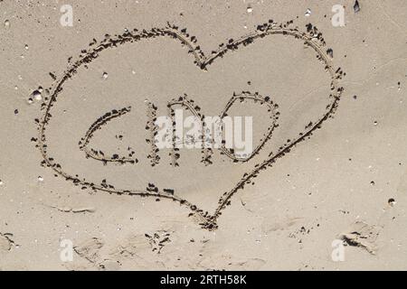 Eine malerische Sandküste mit einem herzförmigen „Ciao“-Schild im Vordergrund Stockfoto