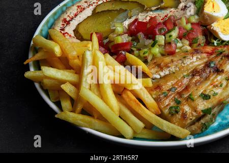 pommes frites mit gebackener Aubergine, gekochten Eiern, Gemüsesalat und Hummus Stockfoto