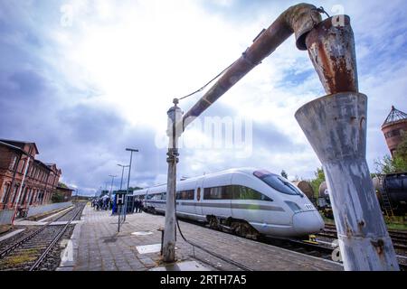 Karow, Deutschland. September 2023. Hinter dem historischen Knickwasserkran zur Wasserversorgung von Dampflokomotiven im Bahnhof Karow steht der Versuchszug „Advanced TrainLab“ der Deutschen Bahn, der sonst kaum genutzt wird. Während eines Zwischenstopps während der Probefahrten hatte der Infrastrukturbetreiber Regio Infra Nordost das Streckenkonzept „Karower Kreuz 365“ für eine effektivere Nutzung des Schienennetzes in der Region vorgestellt. Es geht um mögliche Perspektiven für einen attraktiven Personenverkehr zwischen den Metropolen Berlin und Rostock auf der Nord-Süd-Achse. Quelle: Jens/dpa/Alamy Live News Stockfoto