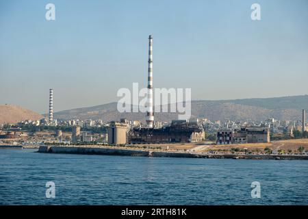 Ruinen von Düngemittelfabriken und Hafen in Piräus Griechenland. Alte verlassene Fabrikindustrieanlage im Hafen. Ruhiges Meer, sonniger Tag, blauer Himmel. Stockfoto