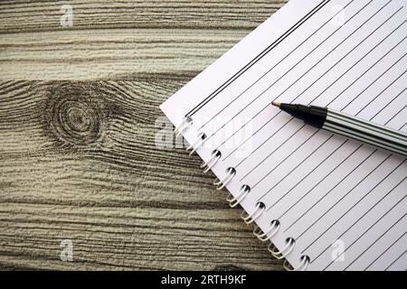 Notizbuch mit Stift auf grauem Holztischhintergrund. Draufsicht mit Kopierbereich (selektiver Fokus). Konzept für Bürotische. Stockfoto