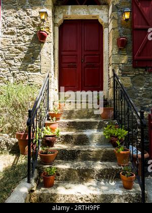 Historisches Steinhaus mit roten Türen und Steintreppen mit Blumentöpfen. Hochwertige Fotos Stockfoto