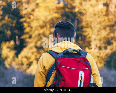 Tausendjähriger Mann, der in gelbem Hoodie und rotem Rucksack wandert und die malerischen Aussichten auf den Wald der Karpaten besteigt. Reise Lifestyle Fernweh in die Wildnis Adv Stockfoto
