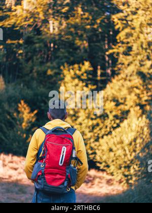 Tausendjähriger Mann, der in gelbem Hoodie und rotem Rucksack wandert und die malerischen Aussichten auf den Wald der Karpaten besteigt. Reise Lifestyle Fernweh in die Wildnis Adv Stockfoto