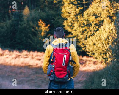 Tausendjähriger Mann, der in gelbem Hoodie und rotem Rucksack wandert und die malerischen Aussichten auf den Wald der Karpaten besteigt. Reise Lifestyle Fernweh in die Wildnis Adv Stockfoto