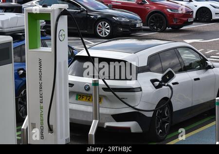 Ein weißes Elektrofahrzeug oder EV, das an einer Tankstelle auf einer Hauptstrecke im Südwesten Englands aufgeladen wird Stockfoto