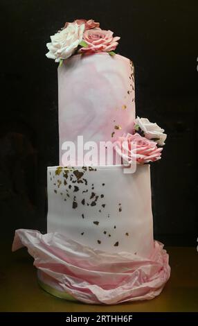 Rosafarbene und weiß geeiste Hochzeitstorte mit Blattgold Stockfoto