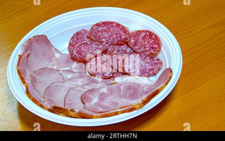 Geräucherte Salami, Peperoni und Schinkenscheiben, in einer Plastikplatte zum Einmalgebrauch Stockfoto