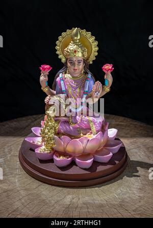 Hindu-Kosmos Maha laxshmi Statue mit Blumengirlande auf schwarzem Hintergrund verziert. Statue der Göttin des Reichtums, Kopierraum, selektiver Fokus. Stockfoto