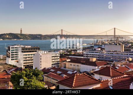 Blick über die Dächer des Hauses, Blick auf den Fluss Tejo, Brücke vom 25. April am Horizont, Abendlicht, Lissabon, Portugal Stockfoto