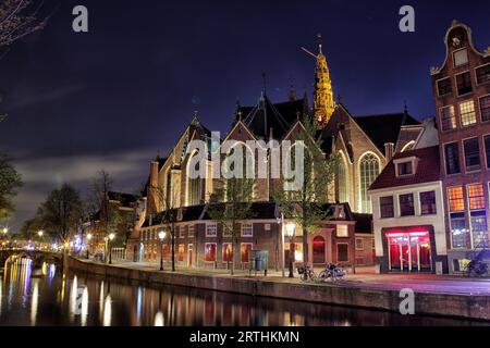 Nächtlicher Blick auf das Oude Kerk, das älteste erhaltene Gebäude in Amsterdam, Niederlande Stockfoto