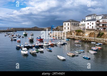 Blick auf den Fischerhafen der asturischen Stadt Tapia de Casariego bei Sonnenuntergang unter bewölktem Himmel. Stockfoto