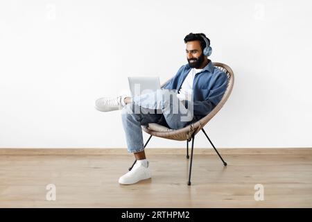 Indischer Bärtiger Mit Laptop Sitzend Mit Kopfhörern Zu Hause Stockfoto