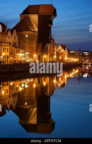 Der Kran in der Abenddämmerung in der Altstadt von Danzig in Polen, Wahrzeichen der mittelalterlichen Stadt mit Wasserreflexion über Mottlau Stockfoto