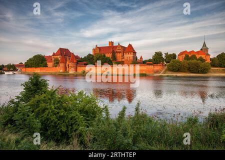 Malbork Castle am Nogat River in Polen, Europa, Sonnenuntergang, die größte mittelalterliche Backsteinburg der Welt, erbaut vom Deutschen Ritterorden Stockfoto